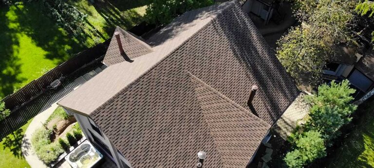 A person using a level to measure the slope of a traditional shingled house roof in winter.