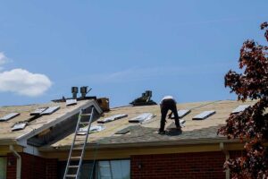 Close view of dented asphalt shingles with loose granules beside a residential roof gutter.