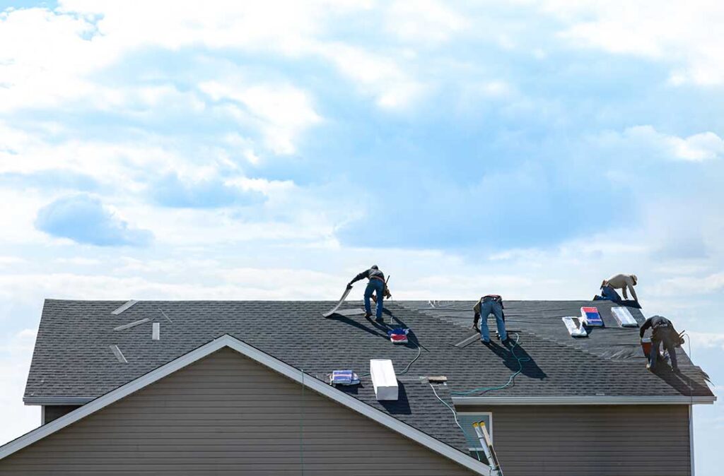 Homeowner examining a ceiling water stain beneath a visibly damaged roof area
